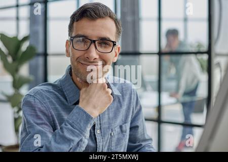 Pensive man in glasses distracted from computer work look in distance thinking or pondering Stock Photo