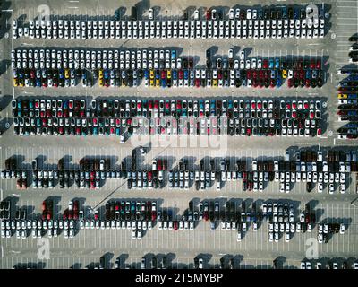 Aerial view of a massive parking lot at a car manufacturing facility with newly produced vehicles parked in rows. Stock Photo
