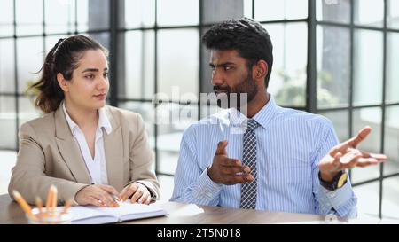 Young indian mentor coach talking with female colleague teaching Stock Photo