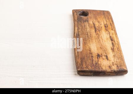 Empty rectangular wooden cutting board on white wooden background. Side view, copy space. Stock Photo