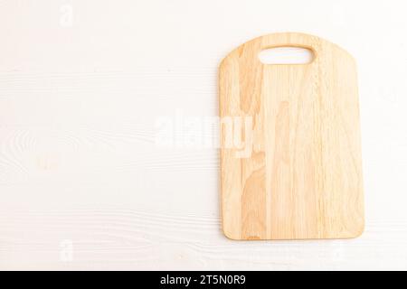 Empty rectangular wooden cutting board on white wooden background. Top view, copy space, flat lay. Stock Photo