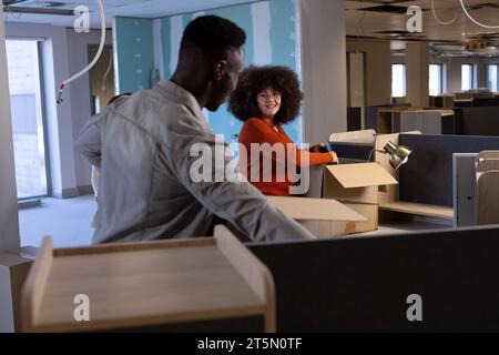 Two happy diverse casual businesspeople packing boxes in renovated office, copy space Stock Photo