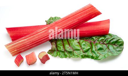Red rhubarb stems' cuts over rhubarb leaves isolated on white background. Stock Photo
