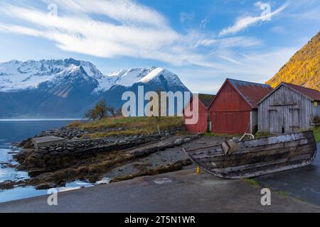 Wooden boat and huts by Hjorundfjorden fjord and Sunnmøre Alps at Urke, Norway, Scandinavia, Europe in October Stock Photo