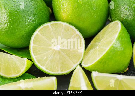 Ripe lime fruits with slices and lime leaves on a gray stone table. Nice fruit citrus background for your projects. Stock Photo