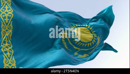 Close-up of Kazakhstan national flag waving on a clear day. Light blue field with a yellow sun and flying eagle in the center and a yellow ornamental Stock Photo