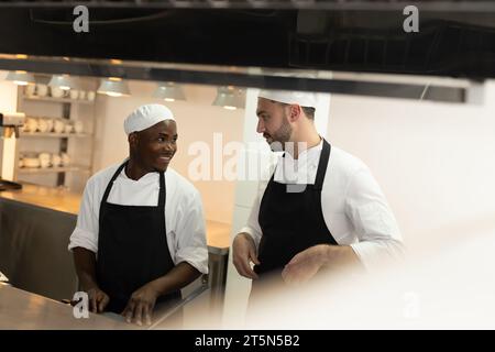 Two diverse male chefs discussing in restaurant kitchen, copy space Stock Photo