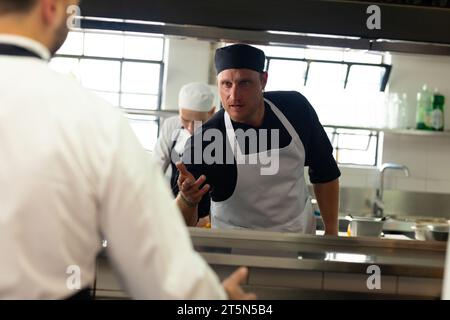 Three caucasian male chefs discussing in restaurant kitchen, copy space ...