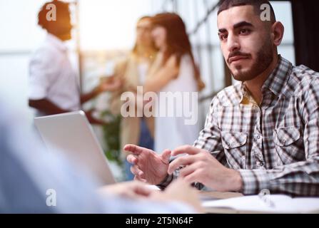 Young adult caucasian male, hiring manager, sits at a desk in a modern office Stock Photo