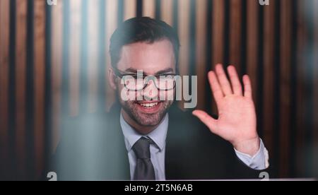 Young handsome businessman goodbye to the client and waves his hand. Stock Photo