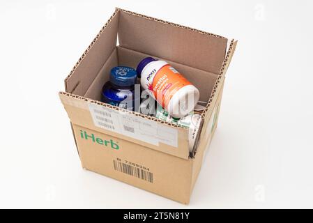 Fuji, Shizuoka, Japan - March 21, 2023: Cardboard box from iHerb online store with supplements: Tryptophan Plus, Inositol 500 mg and Coconut Oil. Isol Stock Photo