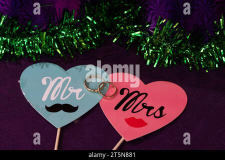 Wedding rings for the bride and groom lie on two heart-shaped signs designating their new status as husband and wife. Stock Photo