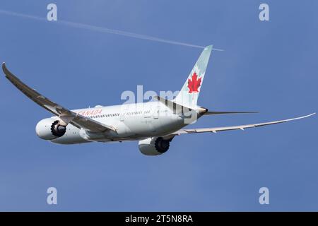 Air Canada Boeing 787 Dreamliner flying out of London Heathrow on an autumn afternoon with a condensation trail from another aircraft in the distance Stock Photo