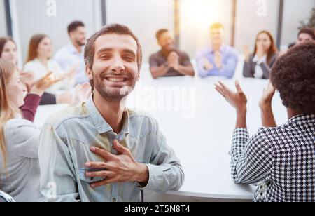 Multiethnic smiling people sitting at desk and looking at camera Stock Photo