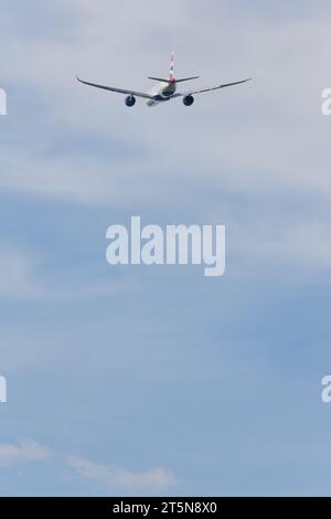 British Airways Airbus A350-1041, registration G-XWBE flying into the distance from London Heathrow in beautiful light on a sunny autumn afternoon Stock Photo