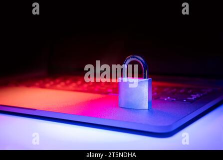 Closeup of a padlock on a laptop illuminated with blue and red light. Phishing, cybersecurity danger or ransomware attack. Encrypted privacy in email. Stock Photo