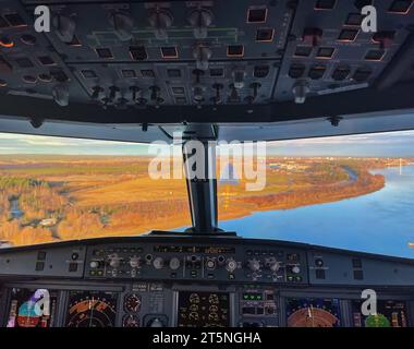 Interior of a jet airplane cockpit on final approach to a runway, at Umeå airport. Clear sky and autumn colors. Stock Photo
