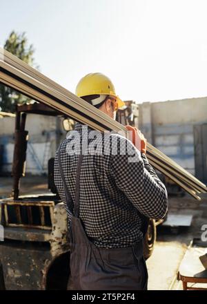 Worker with hard hat carrying wood Stock Photo