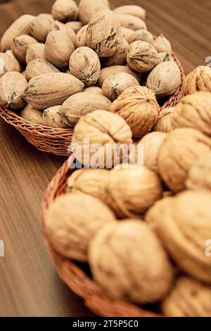 Pecans and walnuts on the table in a wicker basket. Stock Photo
