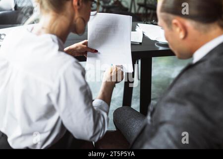 Rear view two businesspeople examining document caf Stock Photo