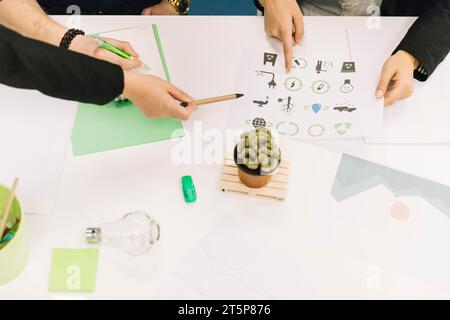 Elevated view businesspeople hands holding paper with energy saving icons Stock Photo
