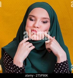 Islamic woman making funny face against yellow backdrop Stock Photo