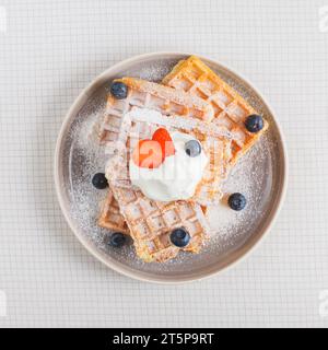 Strawberry blueberry whipped cream stack waffles plate checkered backdrop Stock Photo