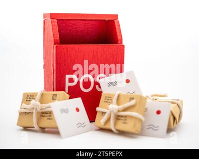 mail delivery concept, parcel boxes of different sizes, letters near a red postal box on white background Stock Photo