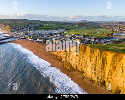 West Bay, Dorset, UK.  6th November 2023.  UK Weather.  Aerial view of the beach and cliffs at West Bay in Dorset which glow golden yellow in the late afternoon autumn sunshine shortly before sunset, after a day of heavy showers.  The beach and cliffs took a battering during Storm Ciaran which flooded a beach cafe and led to a large cliff rockfall.  Picture Credit: Graham Hunt/Alamy Live News Stock Photo