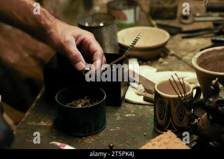 Man working in an old workshop with dim light. Old rusty nutsVintage workplace in the background. Stock Photo