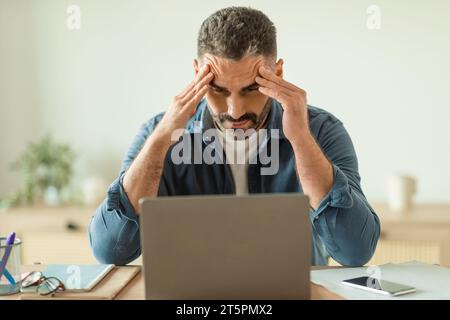 man having stress and headache while looking at laptop indoor Stock Photo