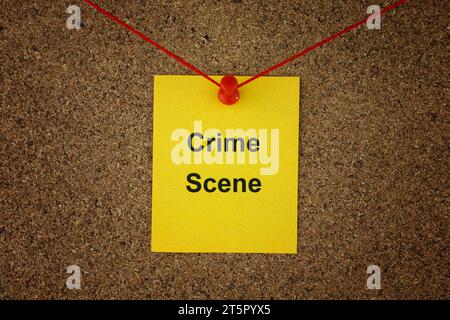 A yellow paper note with the words Crime Scene on it pinned to detective board with red threads. Close up. Stock Photo