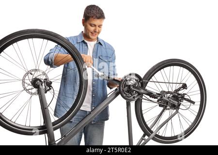 Young man fastening a bicycle pedal with a wrench isolated on white background Stock Photo