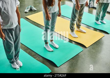 cropped view of four preadolescent boys and girls in sportswear standing on fitness mats, sport Stock Photo