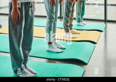 cropped four preadolescent children in sportswear standing on fitness mats, child sport Stock Photo