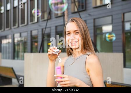 Portrait of happy young woman with flowing hair blows soap bubbles Stock Photo