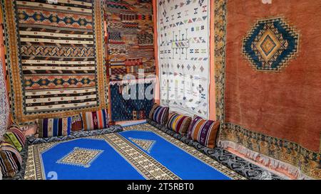 Room full of Moroccan carpets. A Moroccan carpet is a handwoven masterpiece, crafted by skilled artisans. These rugs feature geometric patterns and vi Stock Photo