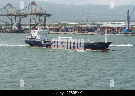 Small oil chemical tanker PANDA PG with blue hull, white superstructure and big rubber fender is leaving port of Kingston. Stock Photo