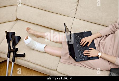 A woman is using her laptop to communicate with a doctor in an online session. Telehealth and digital patient counseling concept. Young woman's fall Stock Photo