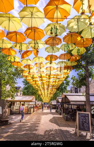 Paris, France - June 16, 2023: Multicolored umbrellas floating in the air at Cour Saint-Emilion in Paris Stock Photo