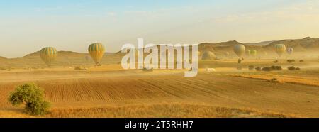 landscape panorama of the hot air balloons of Cappadocia ascend into the sky at dawn. Against the backdrop of a warm and dusky atmosphere above Goreme Stock Photo