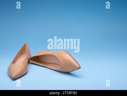 Fancy pointed-toe pastel women's flats on a gradient blue background. One of the shoes is lying on its side. Copy space. Fashion photography Stock Photo