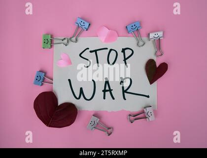 Text messages stop the war with a small pink heart. STOP WAR written on white paper with a pink background. Refugee concept. Stock Photo