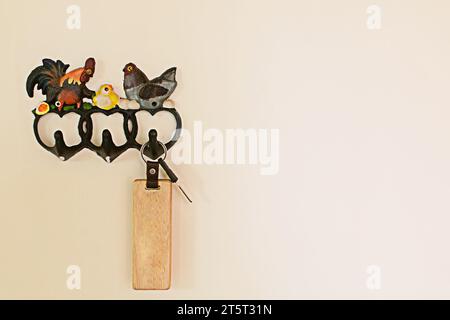 The hook for hanging the key is a rooster on a cement wall. Stock Photo