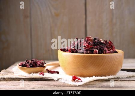 Dry hibiscus tea in bowl on wooden table, space for text Stock Photo