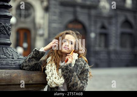 Beautiful young girl with voluminous hair listens to a boring conversation of a mobile operator, notes from her parents, or is upset about a negative Stock Photo