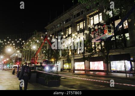 Oxford street outside Selfridges store in September 2023 and the temperature is 22 to 23 degrees and no rain and the time is 2am. There are a few people working hard until 6am so the Christmas lights are put in Oxford street and the west end in general.it is September and there is an economic crisis but that does not seem to bother the council and they are putting Christmas lights up in September . By the time it gets to Christmas the electric bill will be very high it seems 27/9/2023 no credit Stock Photo