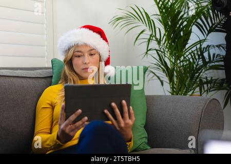 Happy caucasian woman in santa hat using tablet at christmas at home Stock Photo