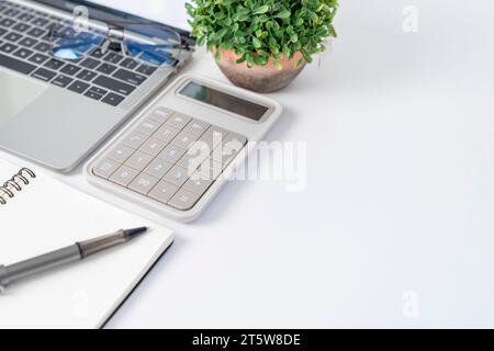Work from home. Desk office with laptop, calculator, blank notepad, coffee cup and pen on wood table. Flat lay top view copy space. Stock Photo