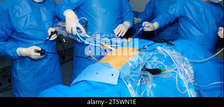 A team of surgeons performs laparoscopic surgery to remove a cancerous tumor in a patient's intestine. Minimally invasive laparoscopic surgery. Stock Photo